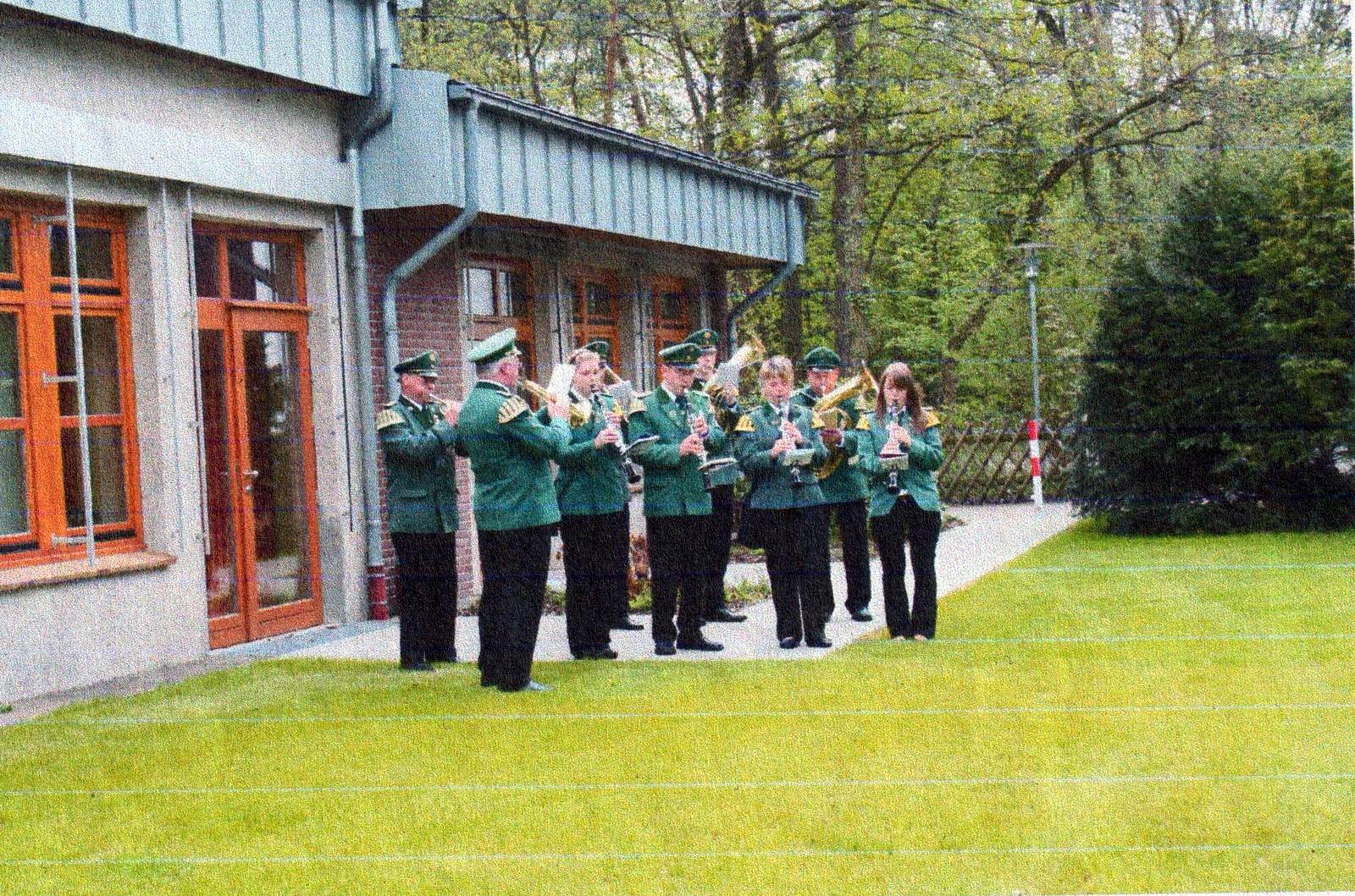 Die Blaskapelle in grünen Uniformen spielt vor dem Kindergartengebäude